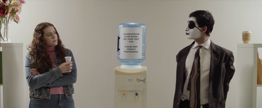 Still from Fools Rush In: a woman and a man in mime makeup stand on either side of an office water cooler