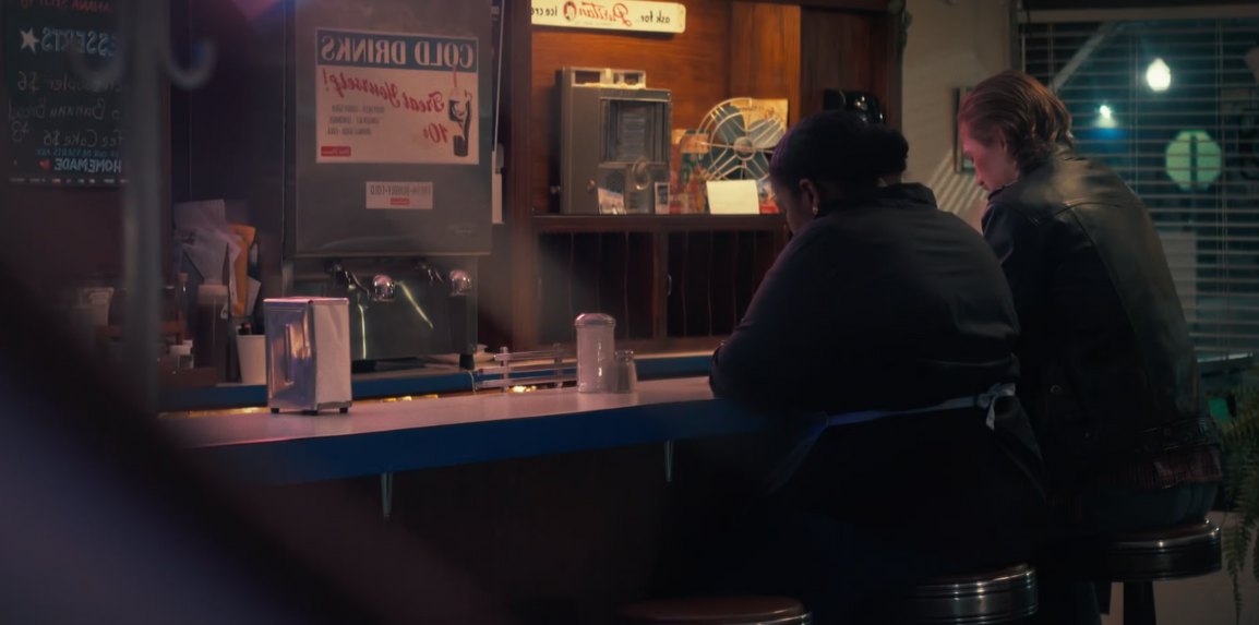 Still from White Knuckle: two people sit at a diner counter, seen through the window